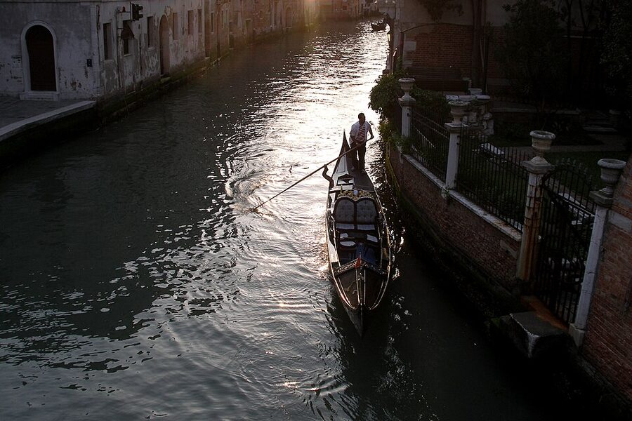 Gondolier rowing in evening sun on a Venice canal