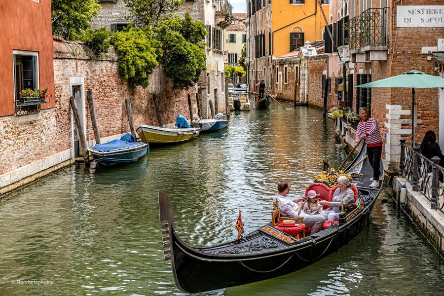 Tourists on a gondola ride in a narrow Venice canal
