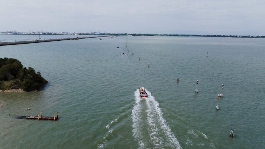 Aerial view of a boat navigating the Venetian lagoon under a cloudy sky