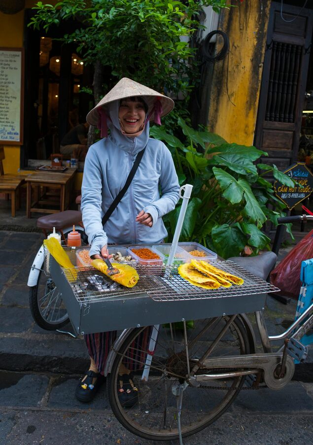 Street vendor cooking food over an open flame at a sidewalk stall in Vietnam