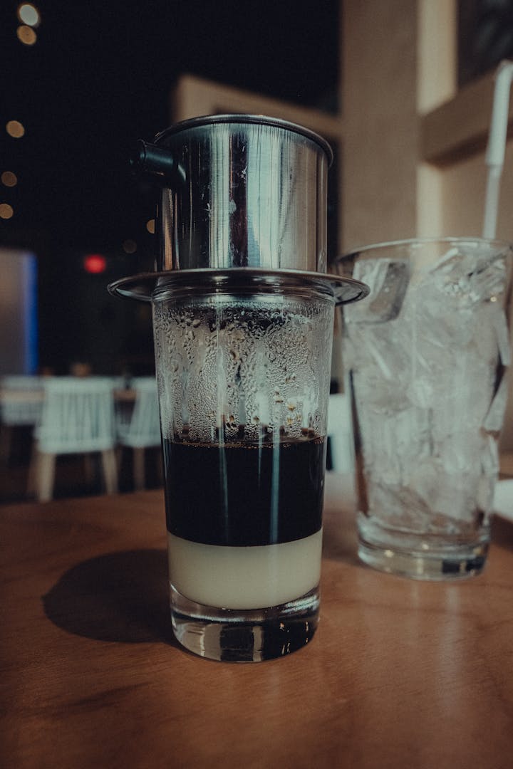 Vietnamese iced coffee with condensed milk being stirred in a tall glass