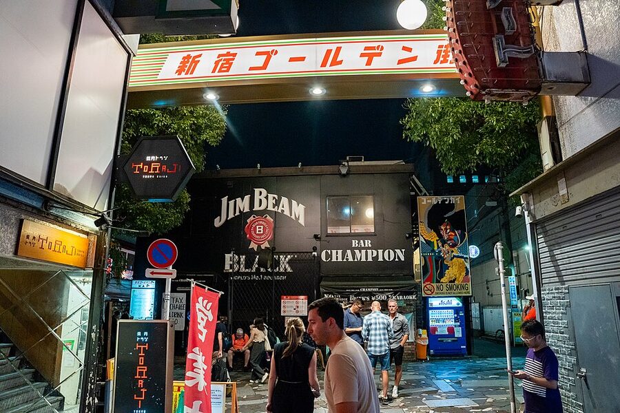 Shinjuku Golden Gai alley in daylight showing low wooden buildings and hand-lettered signage