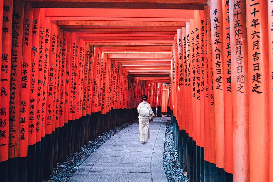 Woman in kimono walking on autumn path