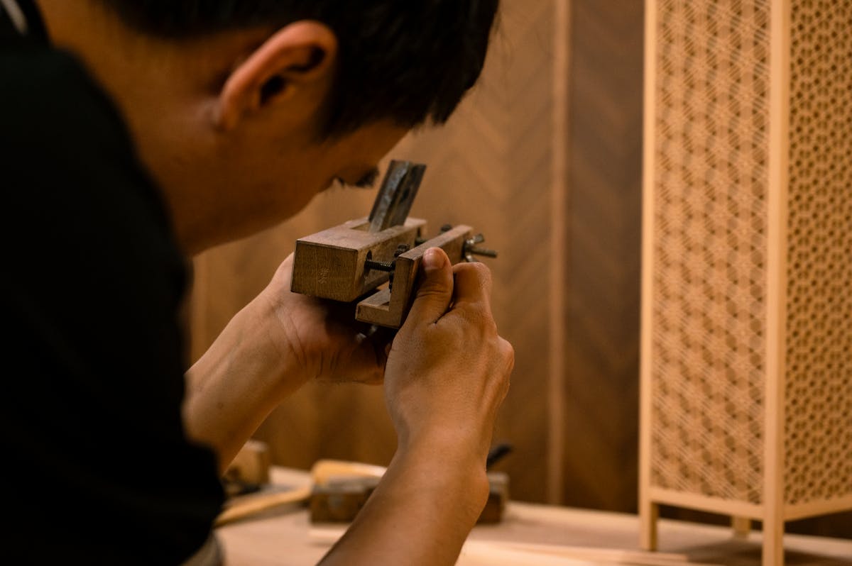 A skilled artisan working on a piece of traditional wood joinery at a workshop bench