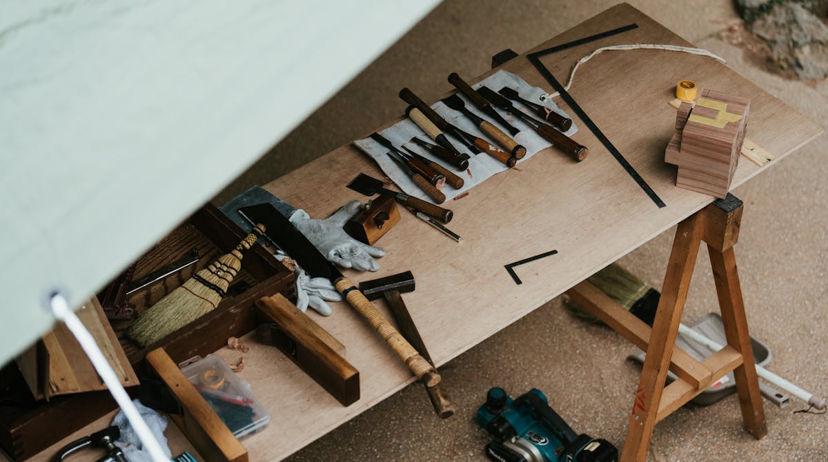 A wooden workbench with various traditional woodworking tools including planes and chisels arranged neatly