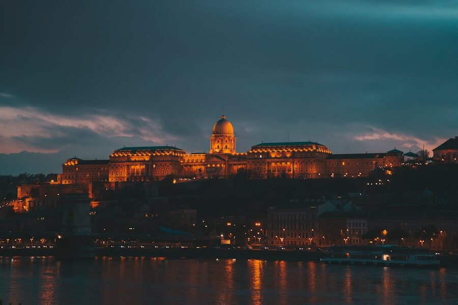 Buda Castle illuminated at dusk seen from across the Danube