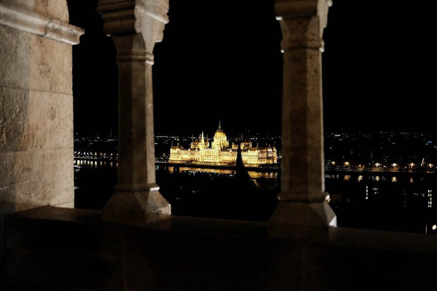 Budapest Parliament framed through stone archway at night