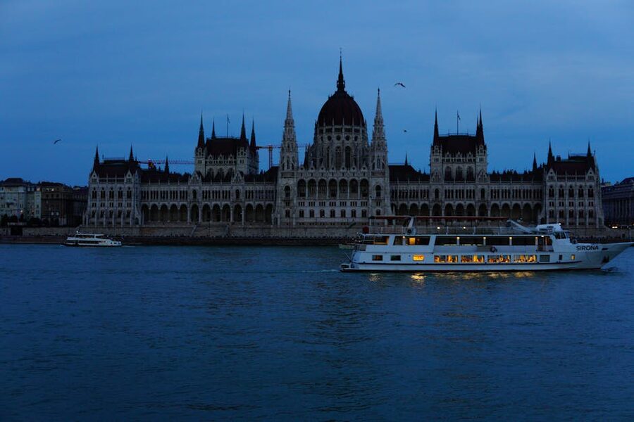 Sightseeing boat passing Budapest Parliament at dusk
