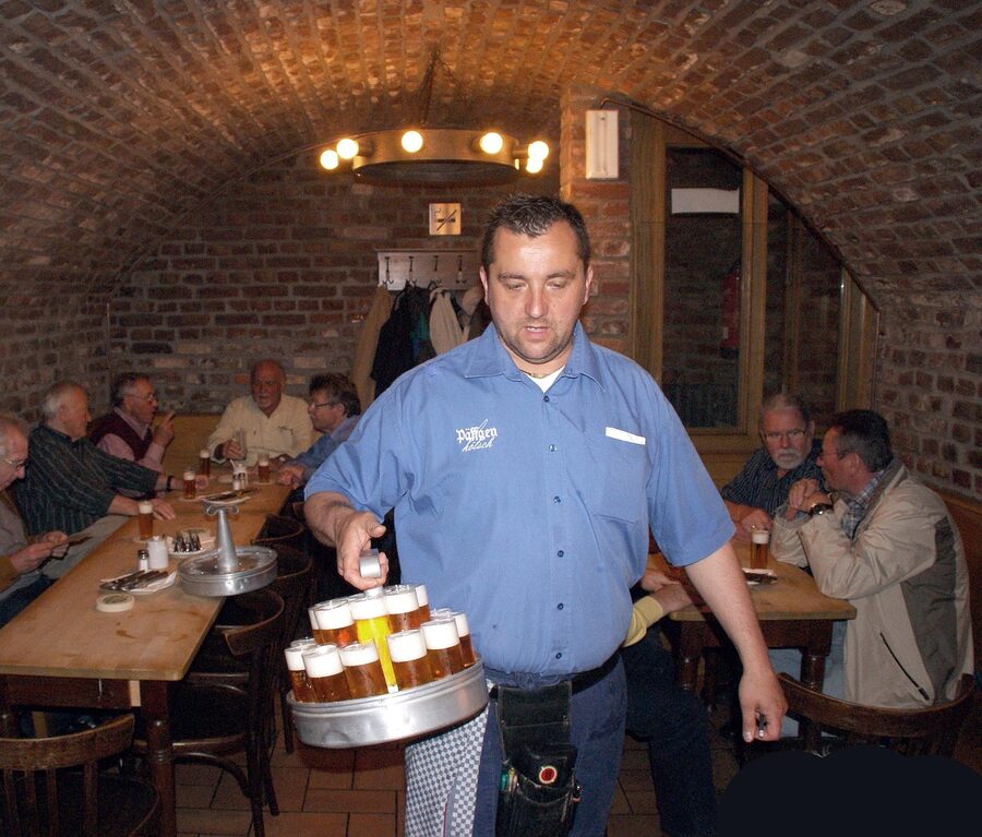A Koebes waiter pouring Koelsch from a Kranz tray at Lommerzheim Cologne