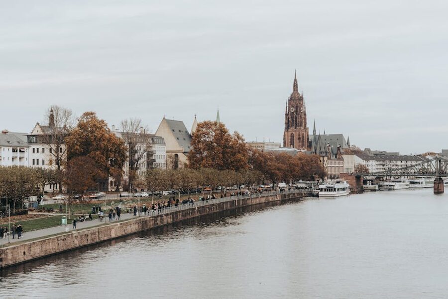 People walking the Mainkai promenade with Frankfurt cathedral in autumn