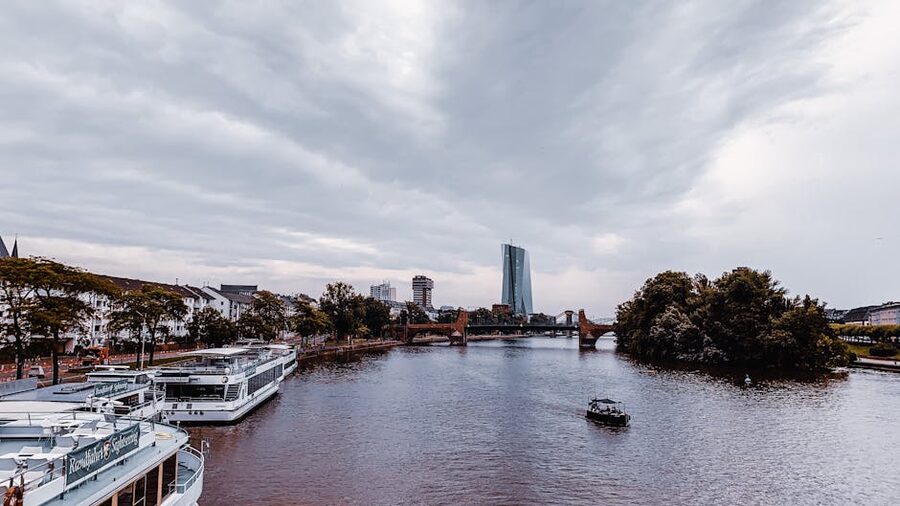 White sightseeing tour boat on the Main River near Frankfurt city buildings