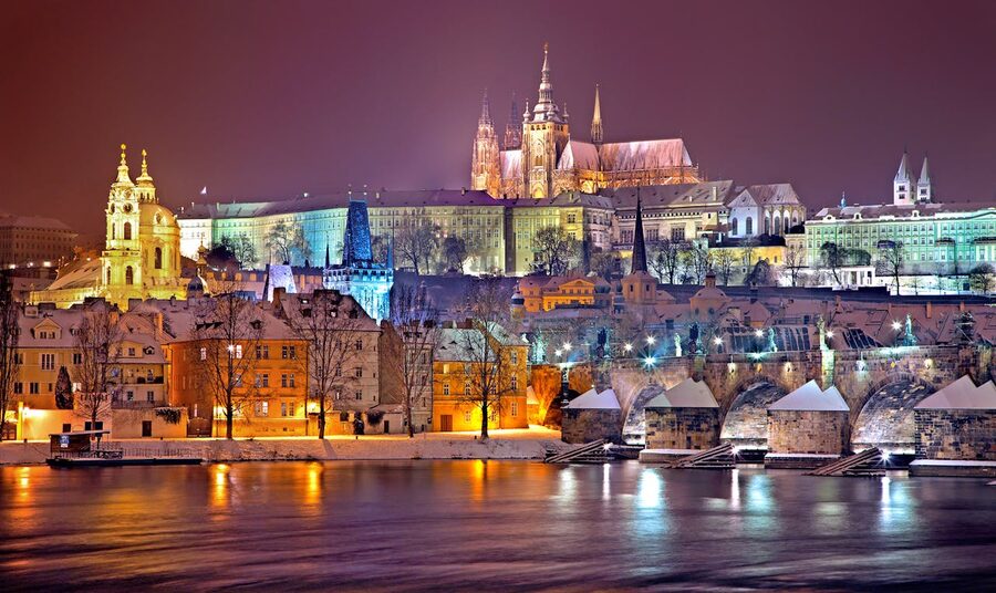 Prague Castle illuminated at night above the Vltava with snow