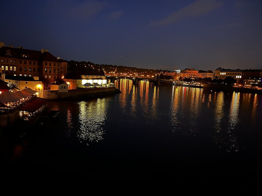 Vltava River at sunset seen from Charles Bridge with cruise boat passing