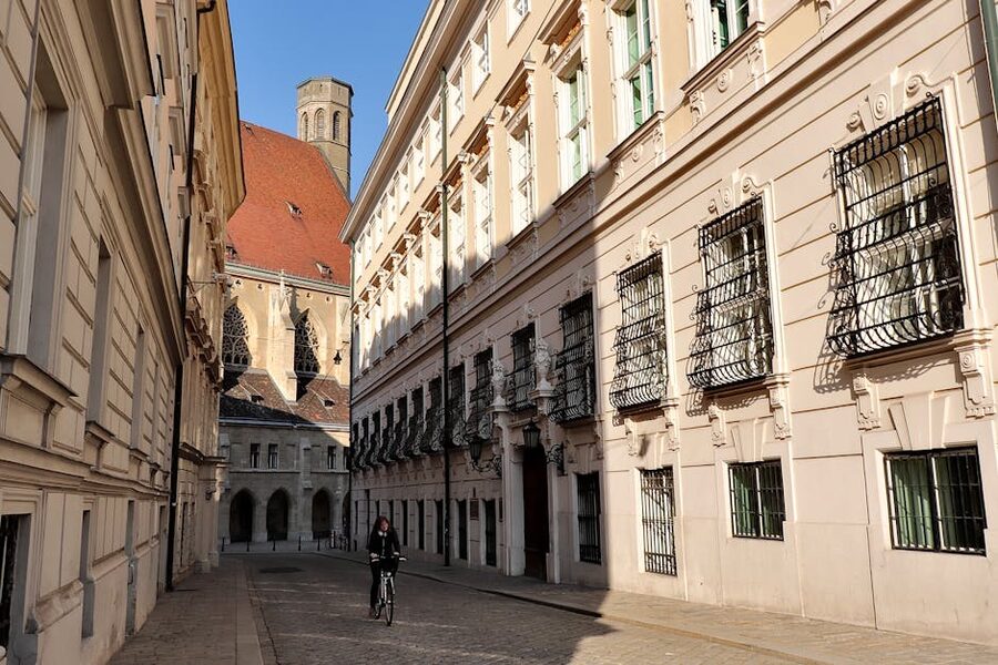 A narrow historic Vienna street with a cyclist passing by